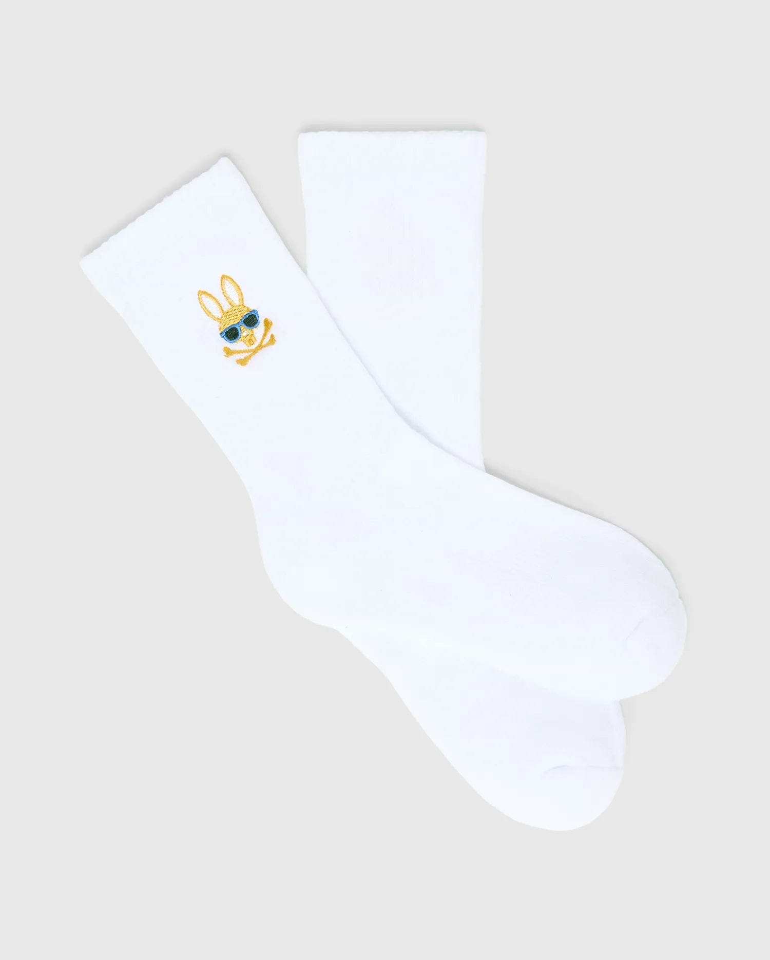 Kids Sunny 3 Pack Sport Socks: White smooth knit sport socks featuring a small, embroidered gold and blue Psycho Bunny skull logo with sunglasses on the ankle cuff.