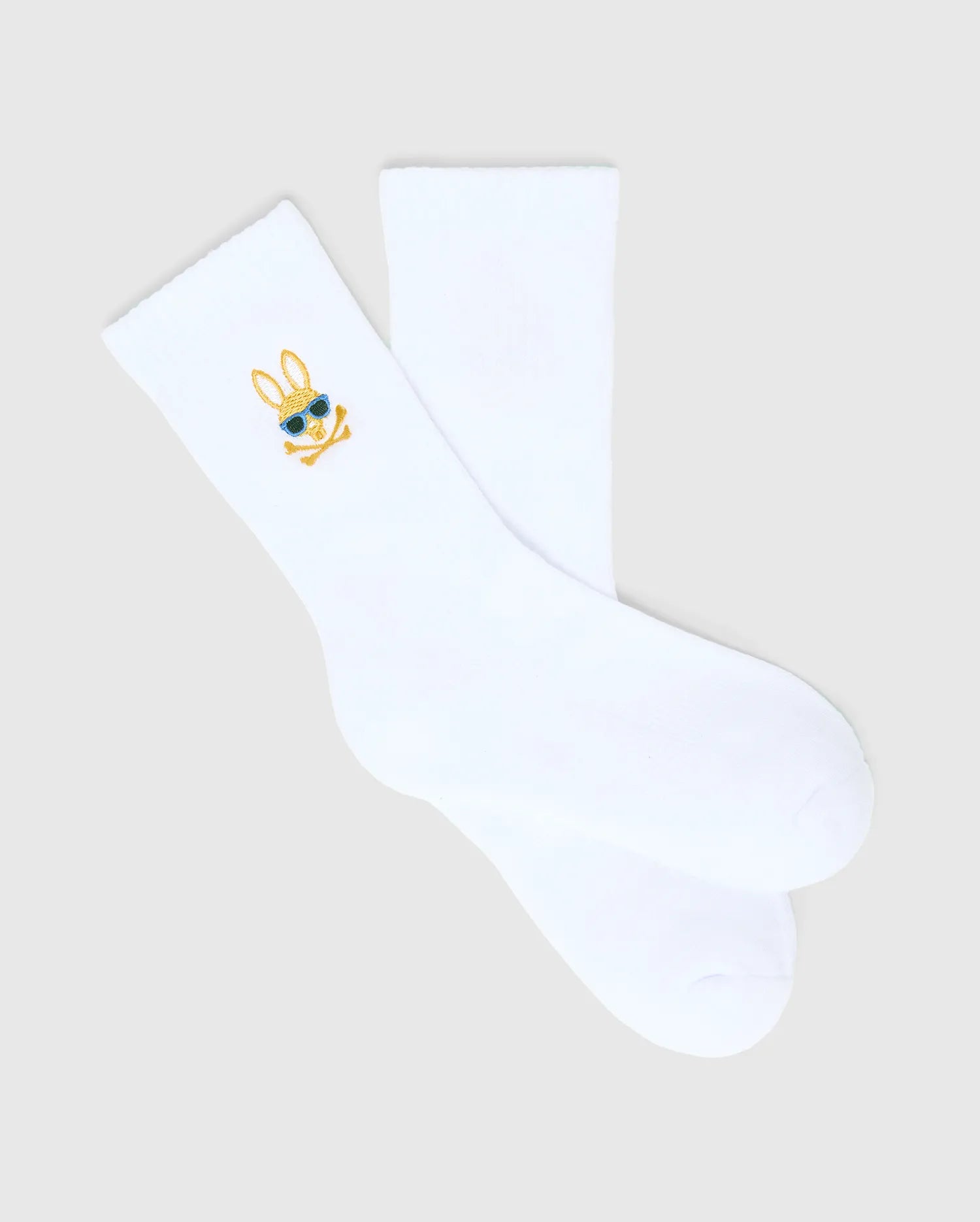 Kids Sunny 3 Pack Sport Socks: White smooth knit sport socks featuring a small, embroidered gold and blue Psycho Bunny skull logo with sunglasses on the ankle cuff.