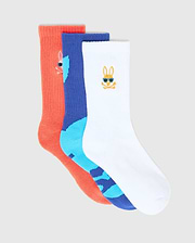 Kids Sunny 3 Pack Sport Socks: a coral ribbed knit, a royal blue and light blue patterned knit, and a white knit sock. Each features a small embroidered Psycho Bunny skull logo, the white one with blue sunglasses.