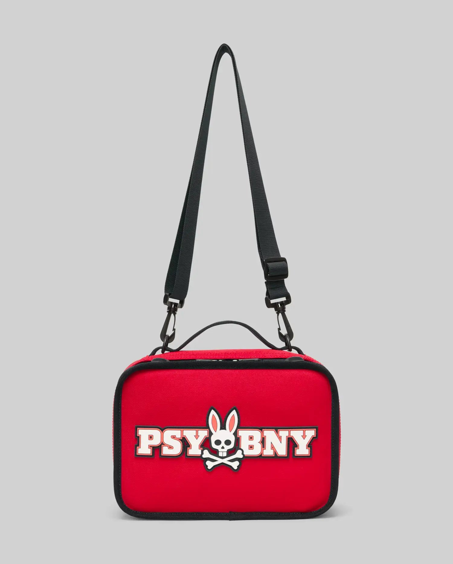 The Psycho Bunny Lunch Box (KO2400002) is a red, rectangular insulated lunch box with a black adjustable strap and handle, featuring a white silicone cartoon bunny skull logo and "PSY BNY" text on the front.