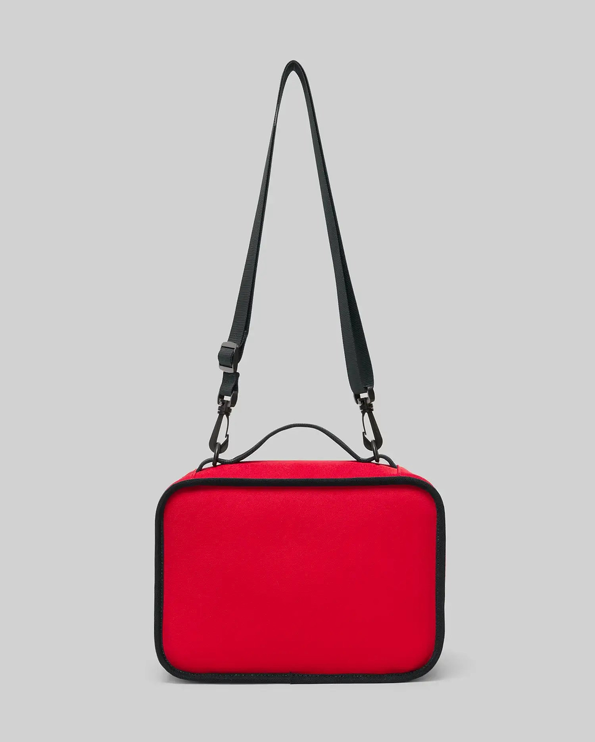 The PSYCHO BUNNY LUNCH BOX - KO2400002 by Psycho Bunny is a rectangular red insulated lunch box featuring a black adjustable shoulder strap and handle, displayed on a plain light gray background.