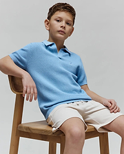 Kids Devon Bubble Stitch Knit Polo in light blue, featuring a textured bubble stitch knit fabric, classic fit, and a small embroidered Psycho Bunny skull logo on the left chest.