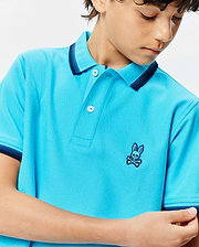 Kids Holden Pique Polo in vibrant aqua blue, classic fit, textured pique fabric, two-button placket, and ribbed collar and cuffs with navy and light blue stripes. Small embroidered Psycho Bunny skull logo on left chest.