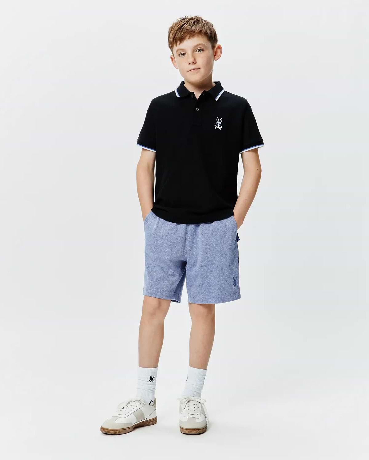 Kids Sunny Pique Polo, black pique with white and blue striped collar/cuffs, white embroidered Psycho Bunny skull logo left chest. Blue heathered shorts with blue embroidered Psycho Bunny logo right leg.