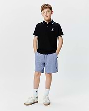 Kids Sunny Pique Polo, black pique with white and blue striped collar/cuffs, white embroidered Psycho Bunny skull logo left chest. Blue heathered shorts with blue embroidered Psycho Bunny logo right leg.