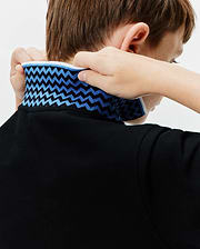 Kids Sunny Pique Polo, a classic fit black pique polo shirt with a bold blue and light blue zigzag pattern on the collar, accented by a crisp white trim.