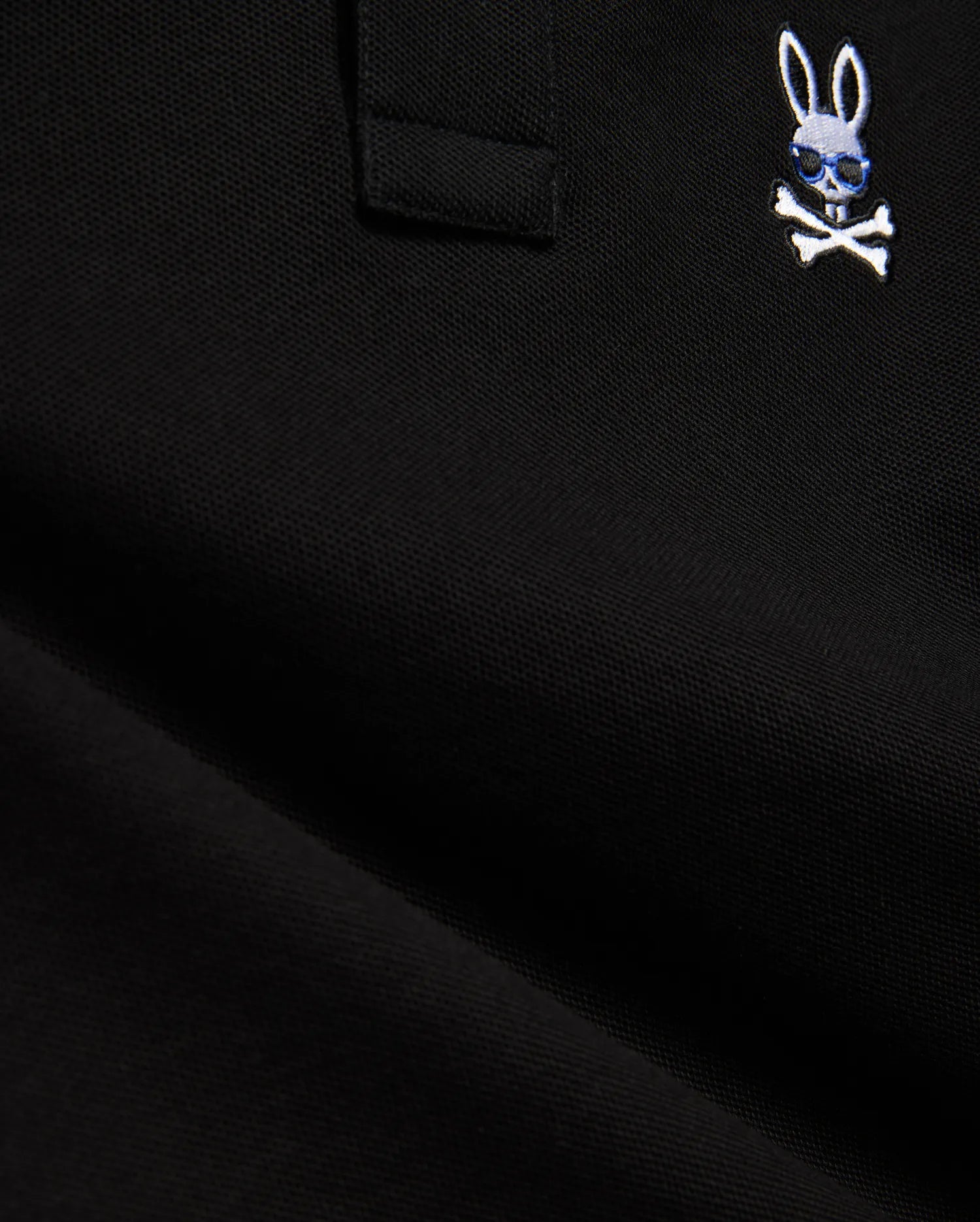 Black Kids Sunny Pique Polo in pique fabric, featuring a small, embroidered white Psycho Bunny skull logo with blue sunglasses and white crossbones on the chest.
