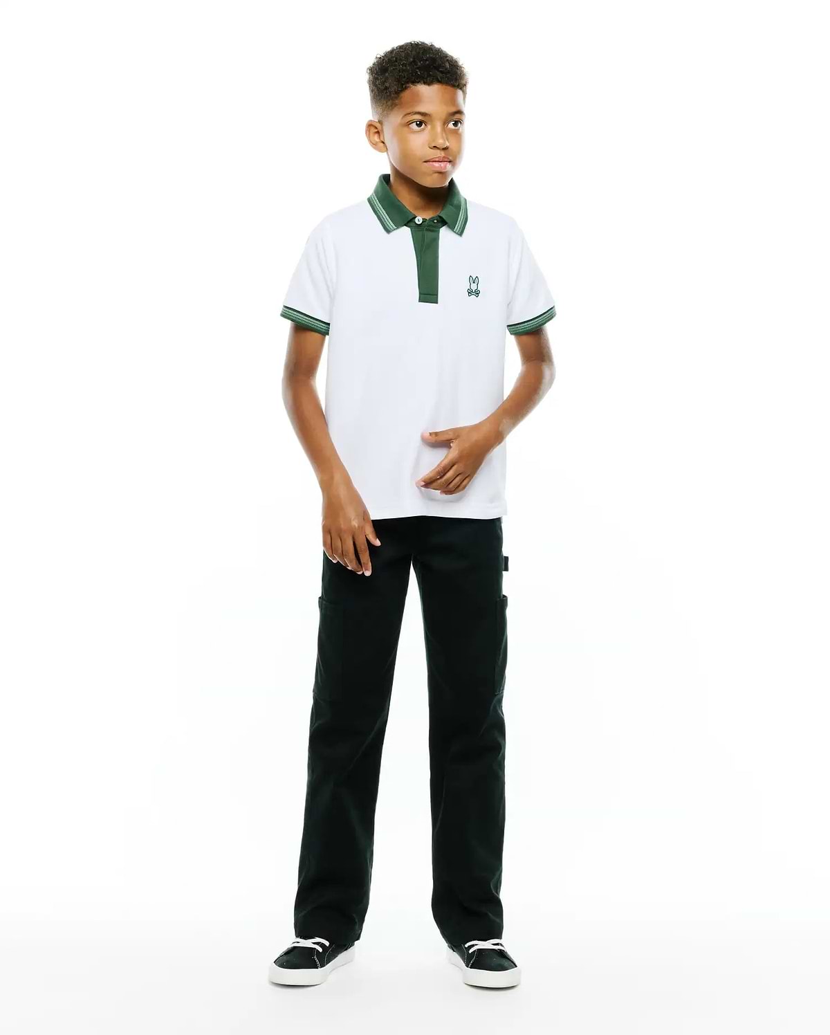 Kids Jaydon Pique Polo, white classic fit pique polo with dark green tipped collar, two-button placket, and cuffs with white stripes, featuring a small embroidered Psycho Bunny skull logo on the left chest.