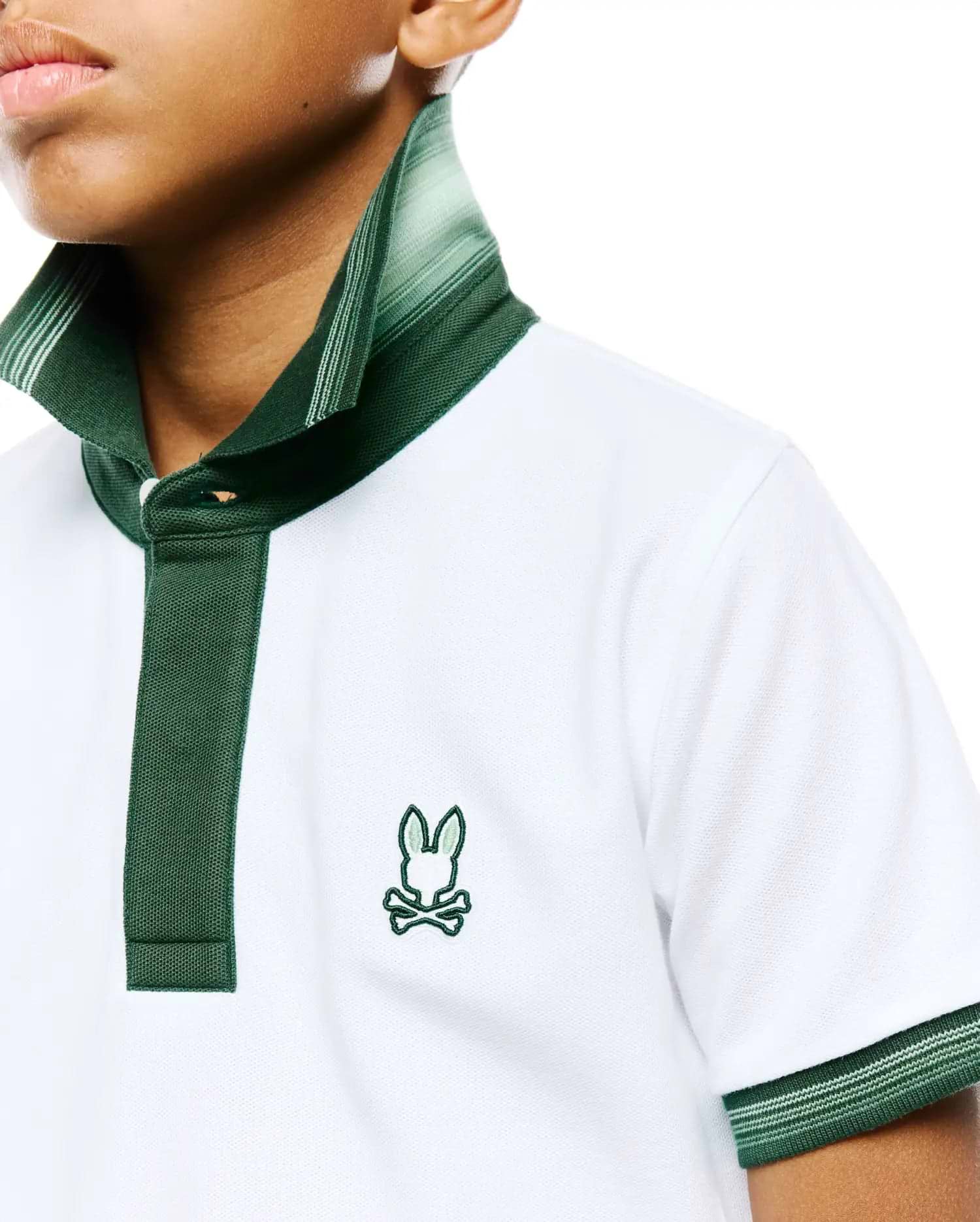 Kids Jaydon Pique Polo in white pique knit, featuring a classic fit, dark green collar, two-button placket, and striped ribbed cuffs, finished with a small embroidered Psycho Bunny skull logo on the left chest.