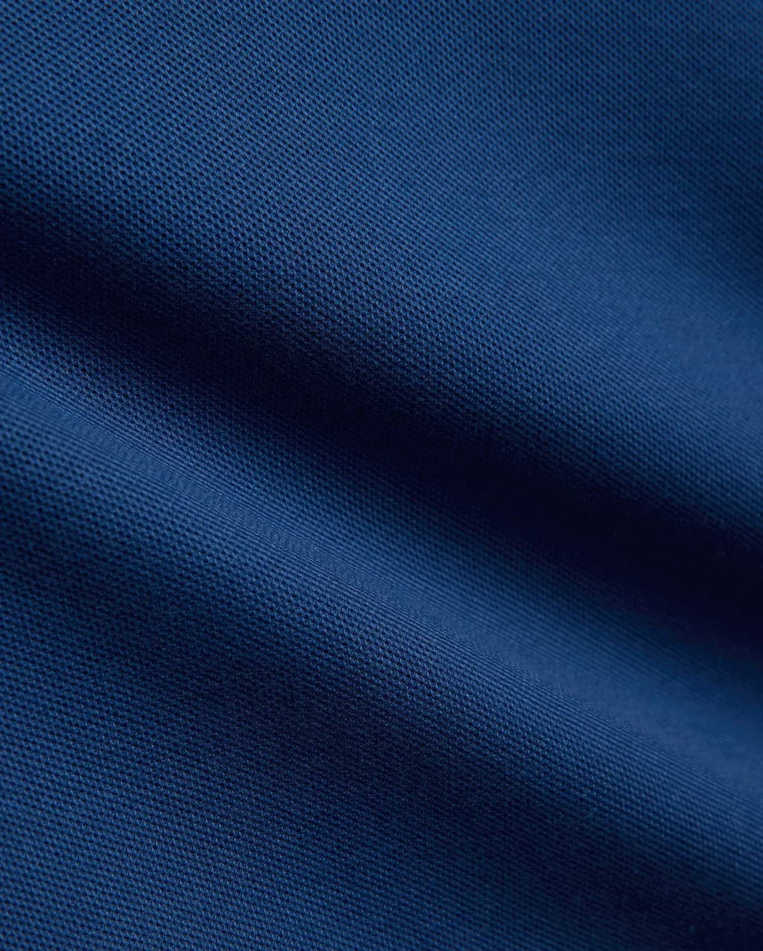 Kids Stan Pique Polo in a rich, dark navy blue, showcasing the classic, breathable textured pique knit fabric with subtle, elegant folds and shadows across its surface.