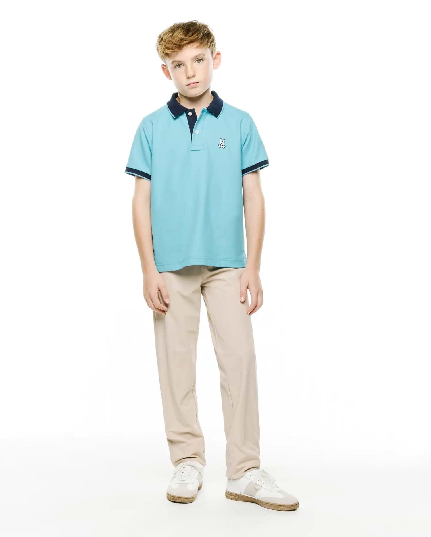 Kids' Klaus Pique Polo, a light blue classic fit pique knit polo with navy collar and sleeve cuffs, featuring a small embroidered Psycho Bunny logo on the left chest. (4)