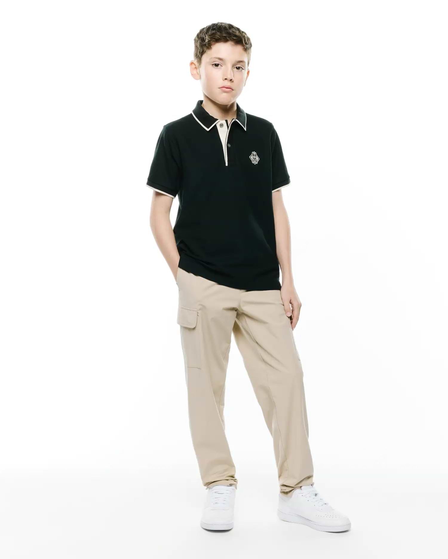 Kids Robin Pique Polo, a classic fit dark green pique polo with white/cream tipping on the collar and cuffs, featuring an embroidered Psycho Bunny skull logo on the left chest.