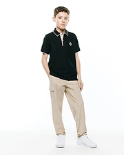 Kids Robin Pique Polo, a classic fit dark green pique polo with white/cream tipping on the collar and cuffs, featuring an embroidered Psycho Bunny skull logo on the left chest.