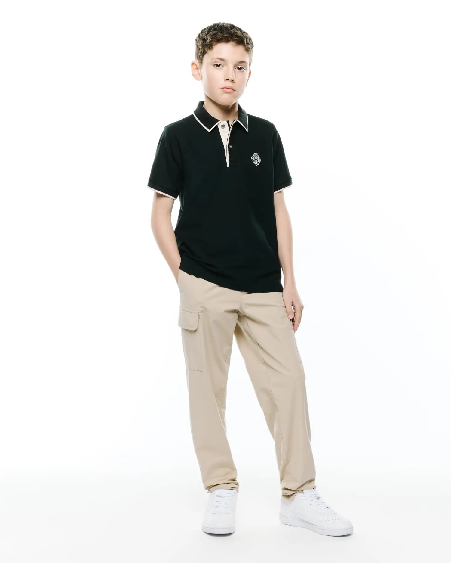 Kids Robin Pique Polo, a classic fit dark green pique polo with white/cream tipping on the collar and cuffs, featuring an embroidered Psycho Bunny skull logo on the left chest.