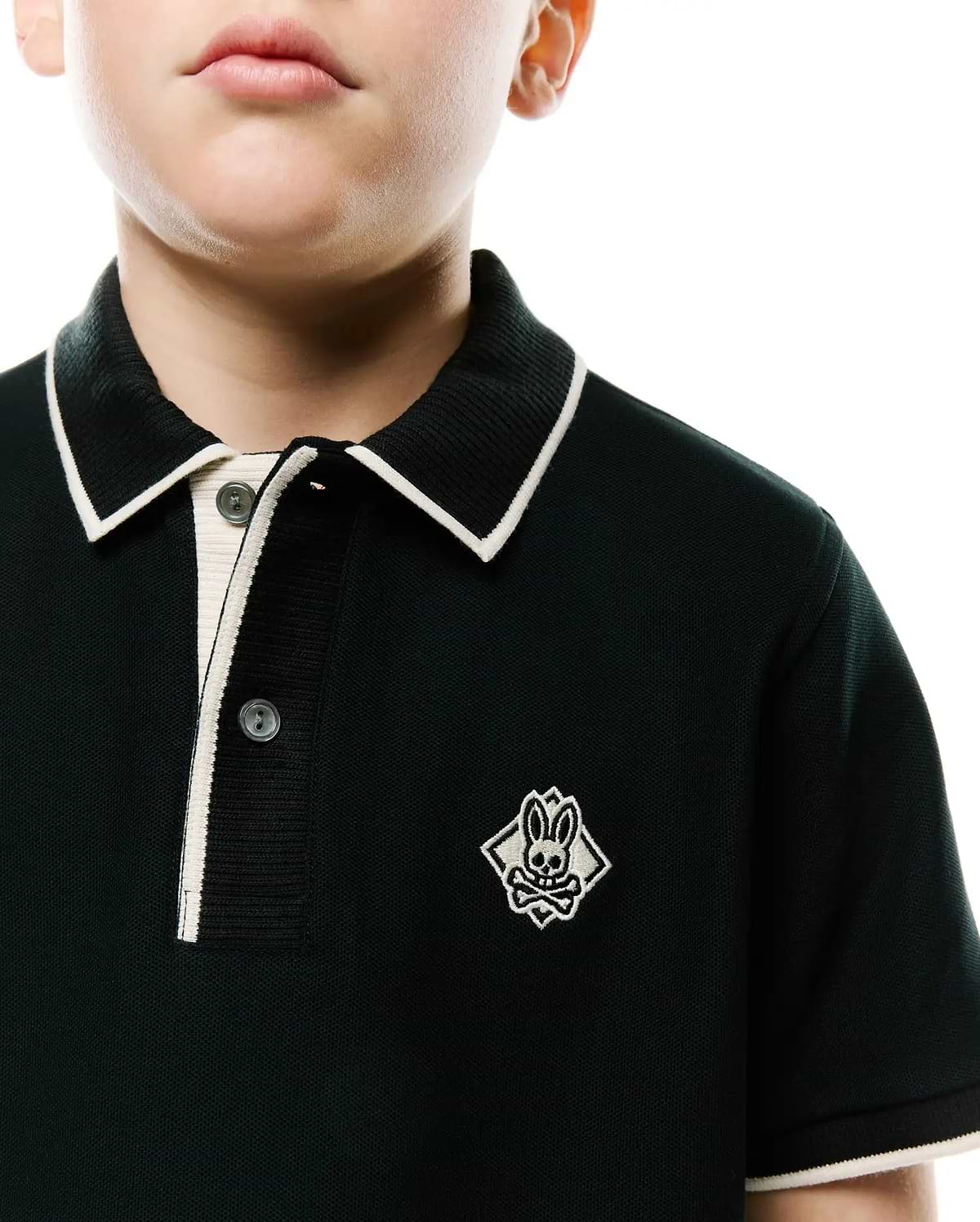 Kids Robin Pique Polo, a dark green classic fit pique knit polo shirt with white tipped collar, placket, and cuffs, featuring an embroidered Psycho Bunny skull logo on the left chest.