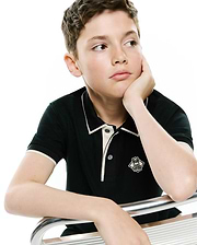 Kids Robin Pique Polo, a premium black pique polo with classic fit, white tipped collar and cuffs, and an embroidered Psycho Bunny skull logo on the left chest.