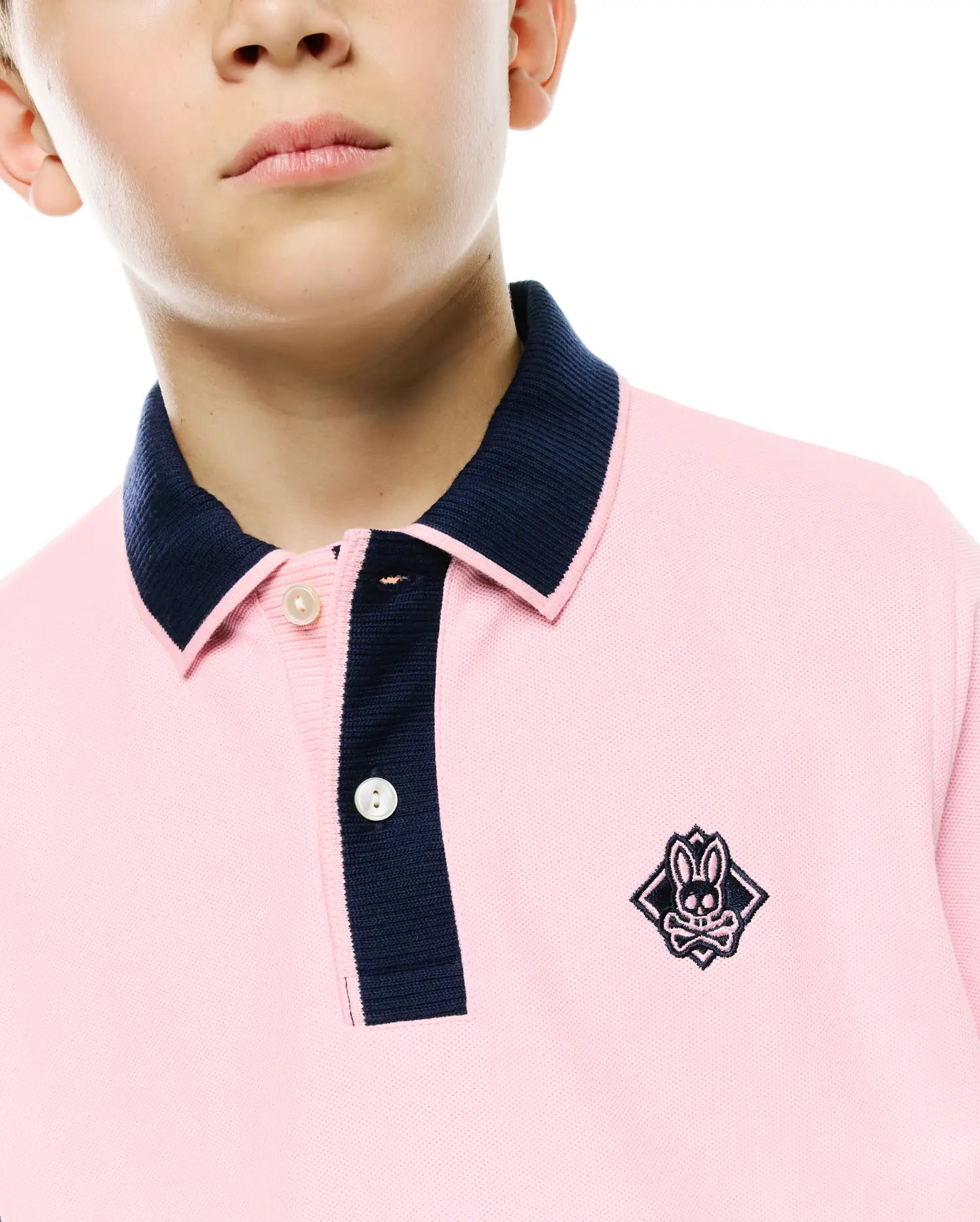 Kids Robin Pique Polo in pink pique knit, featuring a classic fit, navy blue ribbed collar and placket, white buttons, and a small embroidered Psycho Bunny skull logo on the left chest.