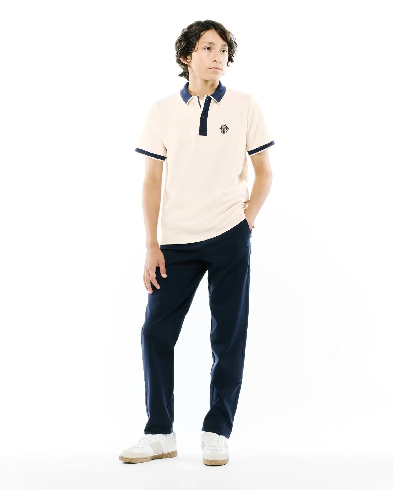 Kids Robin Pique Polo in cream pique with navy blue ribbed collar, two-button placket, and cuffs. Features a small embroidered Psycho Bunny skull logo on the left chest, classic fit.