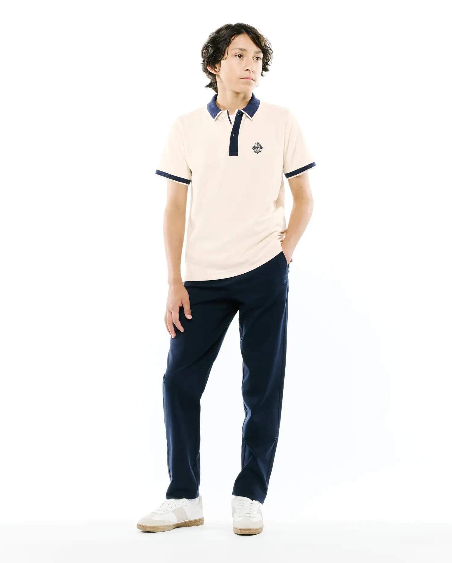 Kids Robin Pique Polo in cream pique with navy blue ribbed collar, two-button placket, and cuffs. Features a small embroidered Psycho Bunny skull logo on the left chest, classic fit.