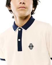 Kids Robin Pique Polo in cream pique knit with navy blue ribbed collar, two-button placket, and cuffs, featuring a small embroidered Psycho Bunny skull logo on the left chest.