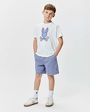 Kids Brad Graphic Tee, a white jersey tee with a large ornate blue Psycho Bunny skull graphic, paired with heather blue relaxed knit shorts featuring a small embroidered bunny logo.