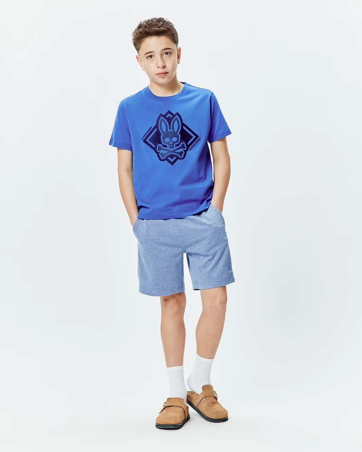 Kids Tobias Graphic Tee in royal blue jersey with a large dark blue Psycho Bunny skull and crossbones diamond graphic on the chest, paired with heather light blue jersey shorts.
