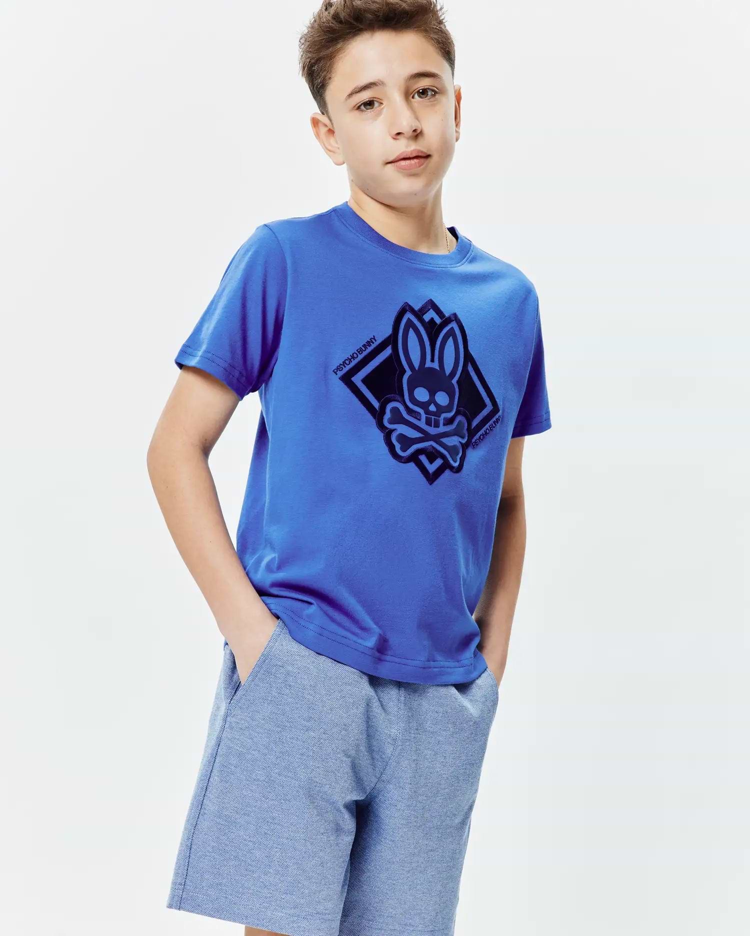 Royal blue Kids Tobias Graphic Tee, a classic fit jersey knit t-shirt featuring a large dark blue Psycho Bunny skull and crossbones logo within a diamond graphic on the center chest.