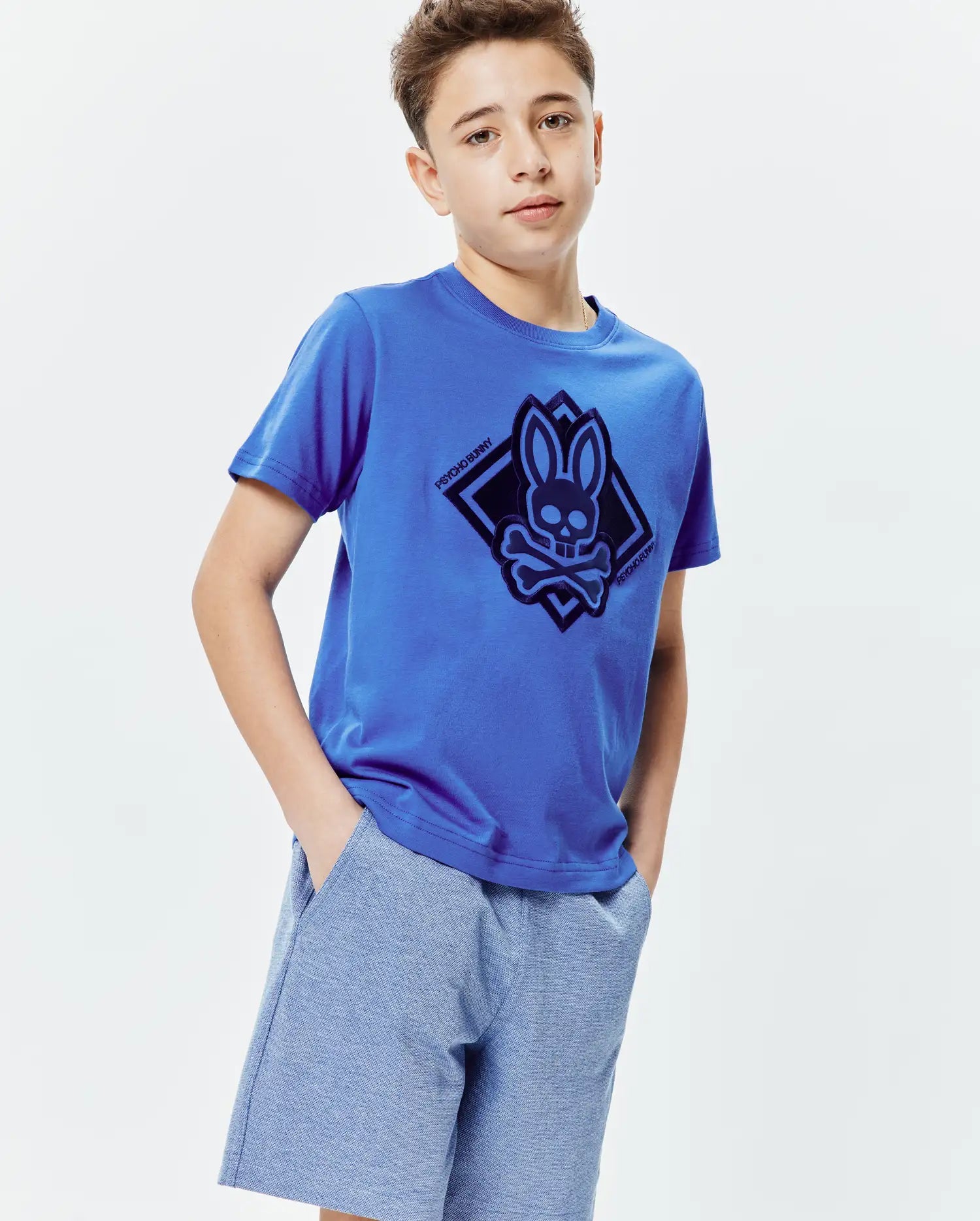 Royal blue Kids Tobias Graphic Tee, a classic fit jersey knit t-shirt featuring a large dark blue Psycho Bunny skull and crossbones logo within a diamond graphic on the center chest.