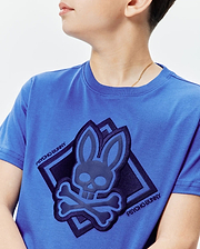 Kids Tobias Graphic Tee: Royal blue classic fit jersey t-shirt with a large central raised dark navy Psycho Bunny skull and crossbones logo in a diamond, plus Psycho Bunny text.