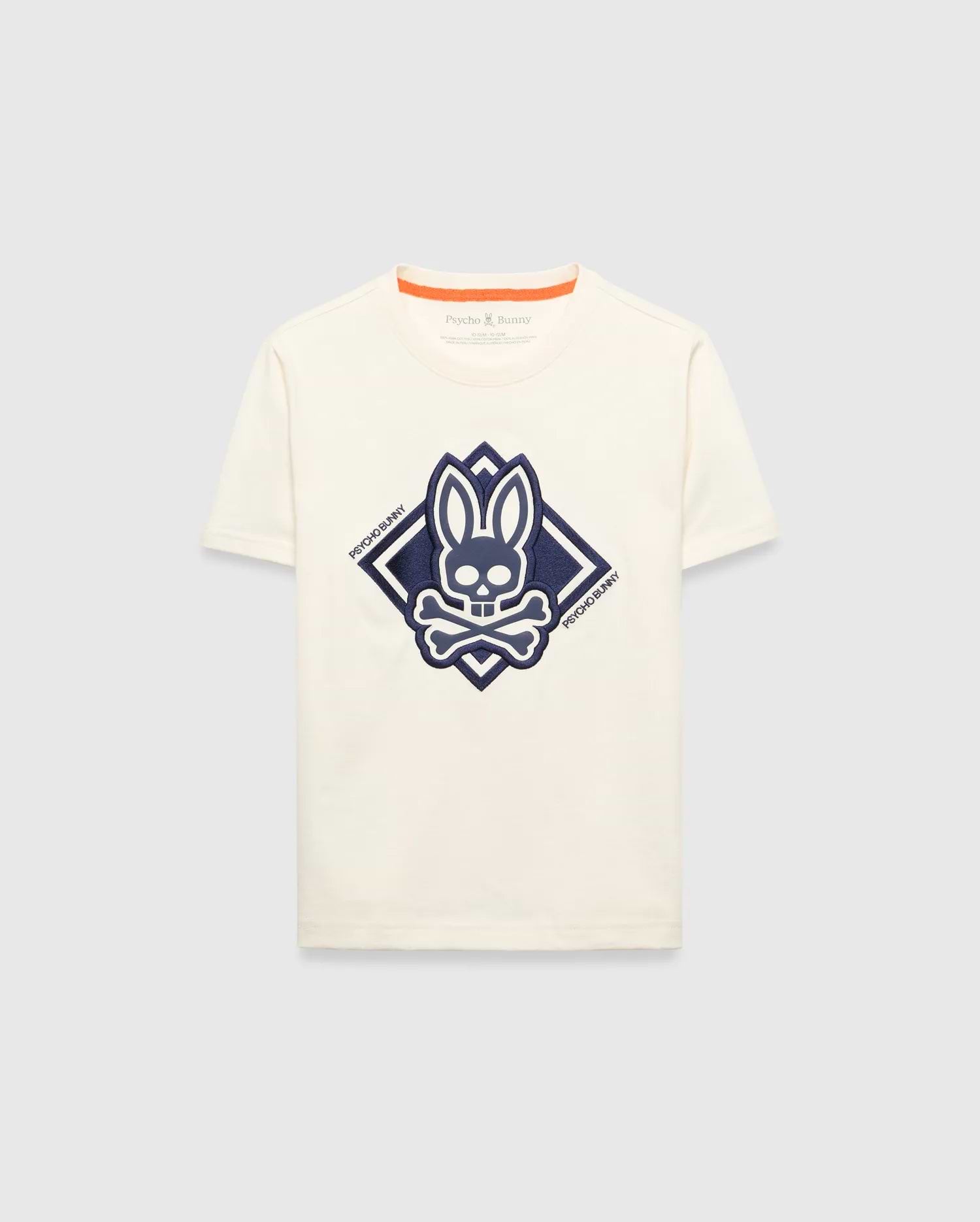 Kids Tobias Graphic Tee, a classic fit cream jersey t-shirt with a large, textured navy blue Psycho Bunny skull and crossbones logo graphic inside a diamond on the chest, featuring orange neckline trim.