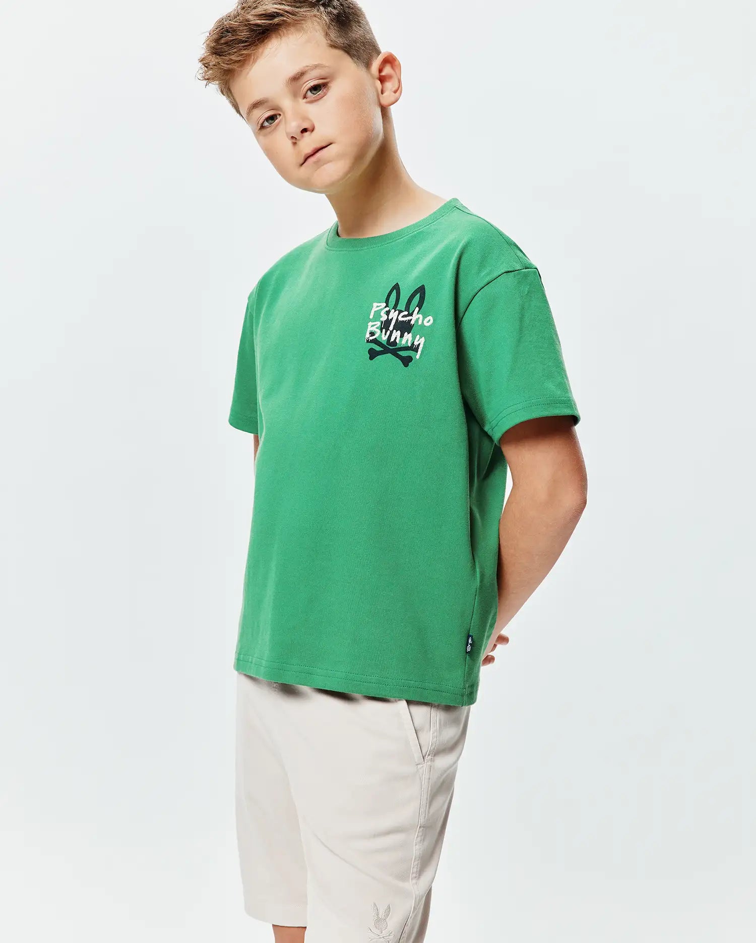 Kids Duncan Relaxed Fit Tee in vibrant green jersey, featuring a large white and black Psycho Bunny skull graphic on the left chest and a small woven logo tag on the hem.