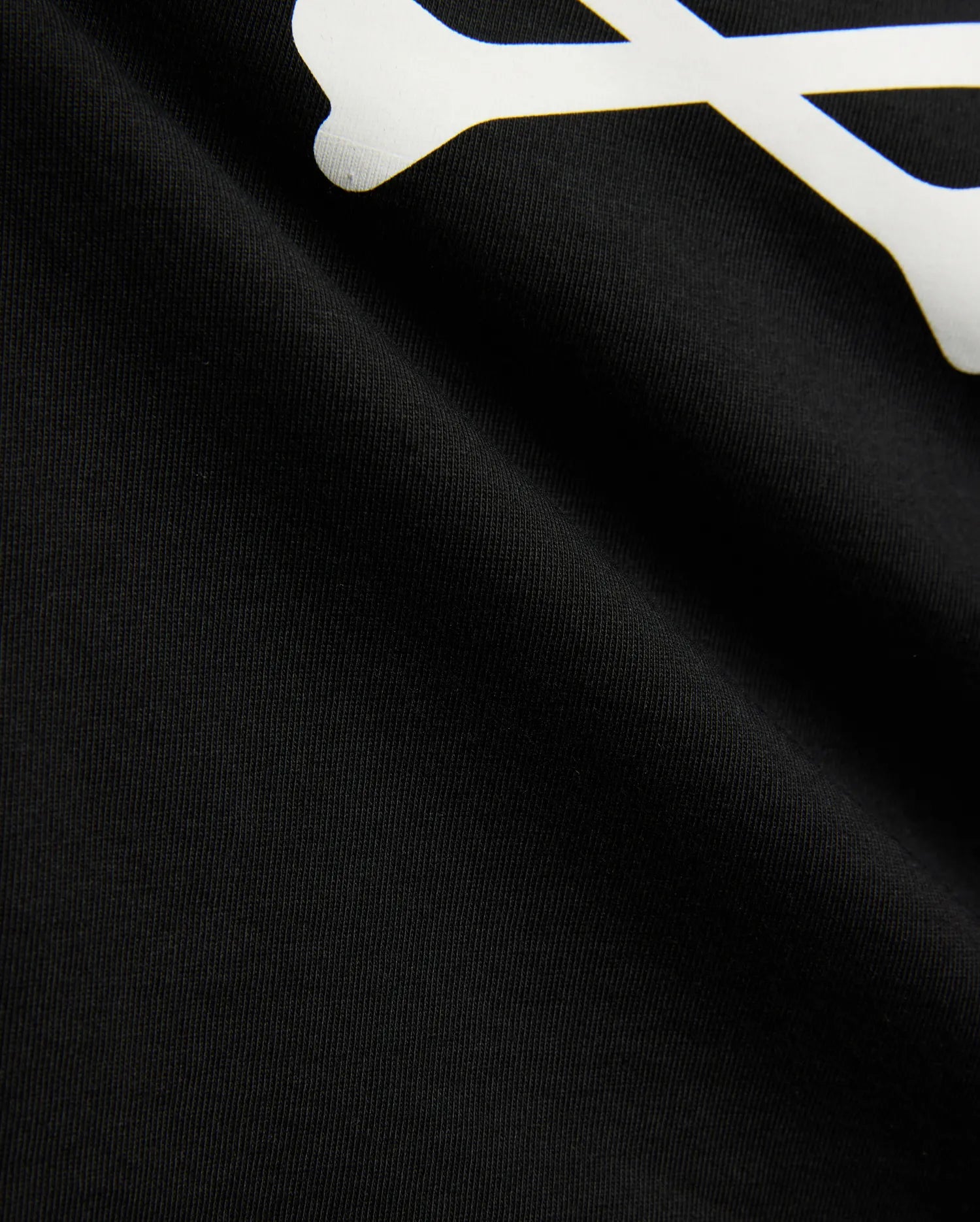 Kids Sunny Graphic Tee in black jersey knit, showcasing a large white graphic print of a bone, a key element of the iconic Psycho Bunny skull and crossbones logo.