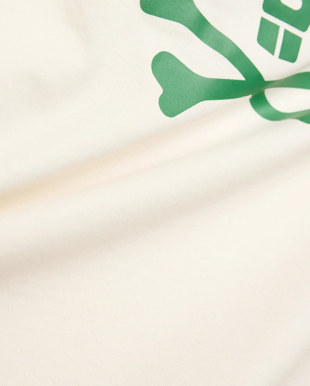 Kids Sunny Graphic Tee crafted from soft cream jersey knit, showcasing a prominent, vibrant green Psycho Bunny skull and crossbones graphic print for a comfortable classic fit.