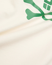 Kids Sunny Graphic Tee crafted from soft cream jersey knit, showcasing a prominent, vibrant green Psycho Bunny skull and crossbones graphic print for a comfortable classic fit.