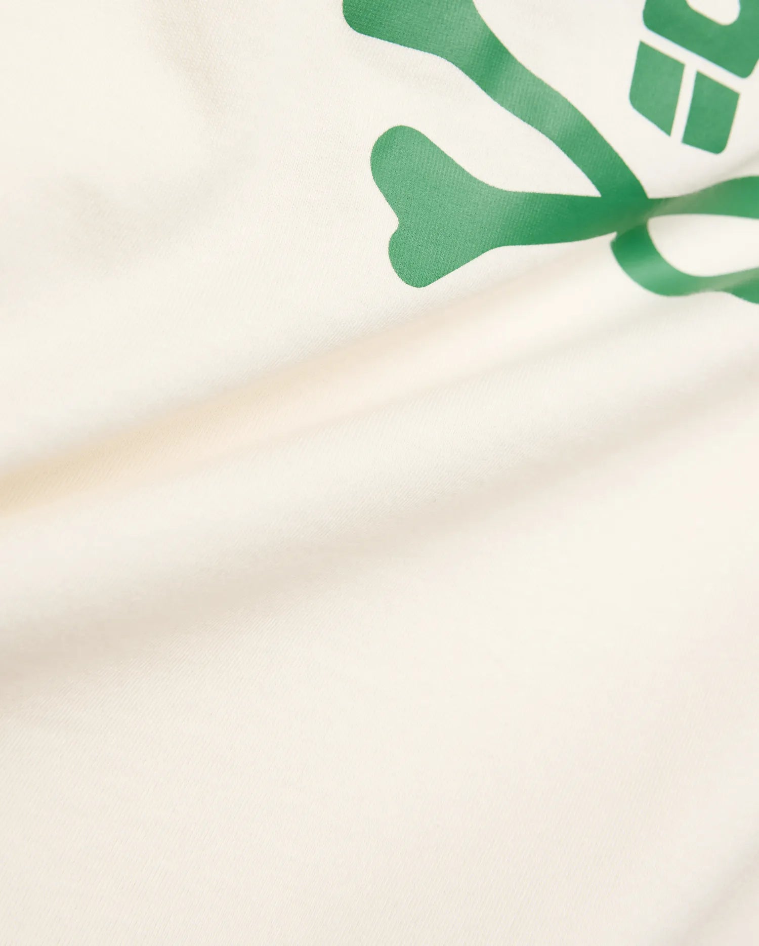 Kids Sunny Graphic Tee crafted from soft cream jersey knit, showcasing a prominent, vibrant green Psycho Bunny skull and crossbones graphic print for a comfortable classic fit.