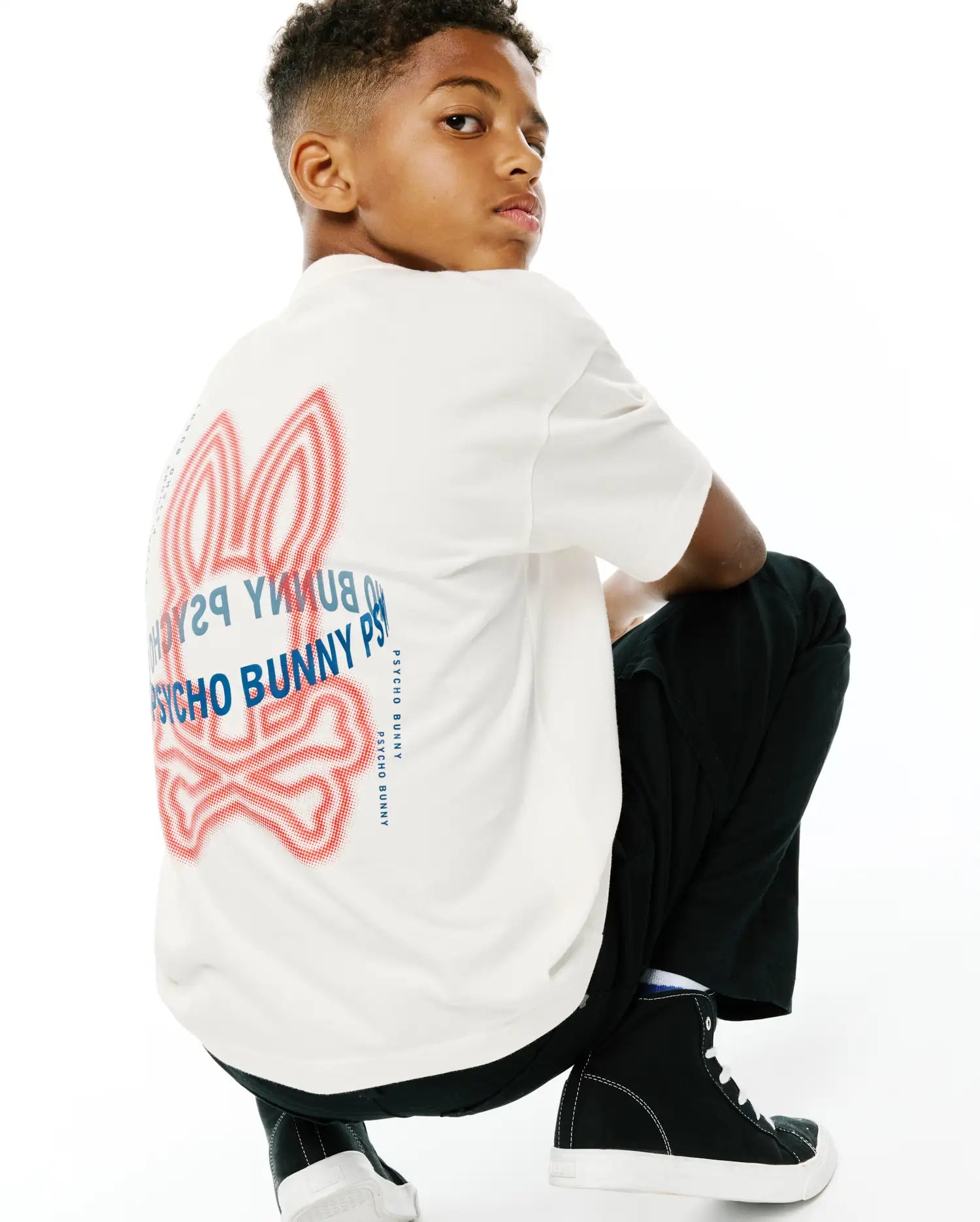 Kids Alex Relaxed Back Graphic Tee, a cream soft jersey relaxed fit t-shirt featuring a large red dotted outline Psycho Bunny skull logo and blue Psycho Bunny text graphic on the back.