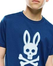 Kids Emmanuel Graphic Tee in navy blue, featuring a classic fit and soft jersey knit. A prominent, large white spray-paint effect Psycho Bunny skull and crossbones graphic adorns the central chest.
