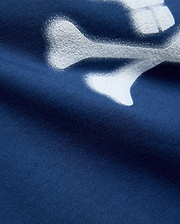 Kids Emmanuel Graphic Tee in deep navy jersey knit, featuring a large, distressed white graphic of a bone, part of the iconic Psycho Bunny skull and crossbones logo.
