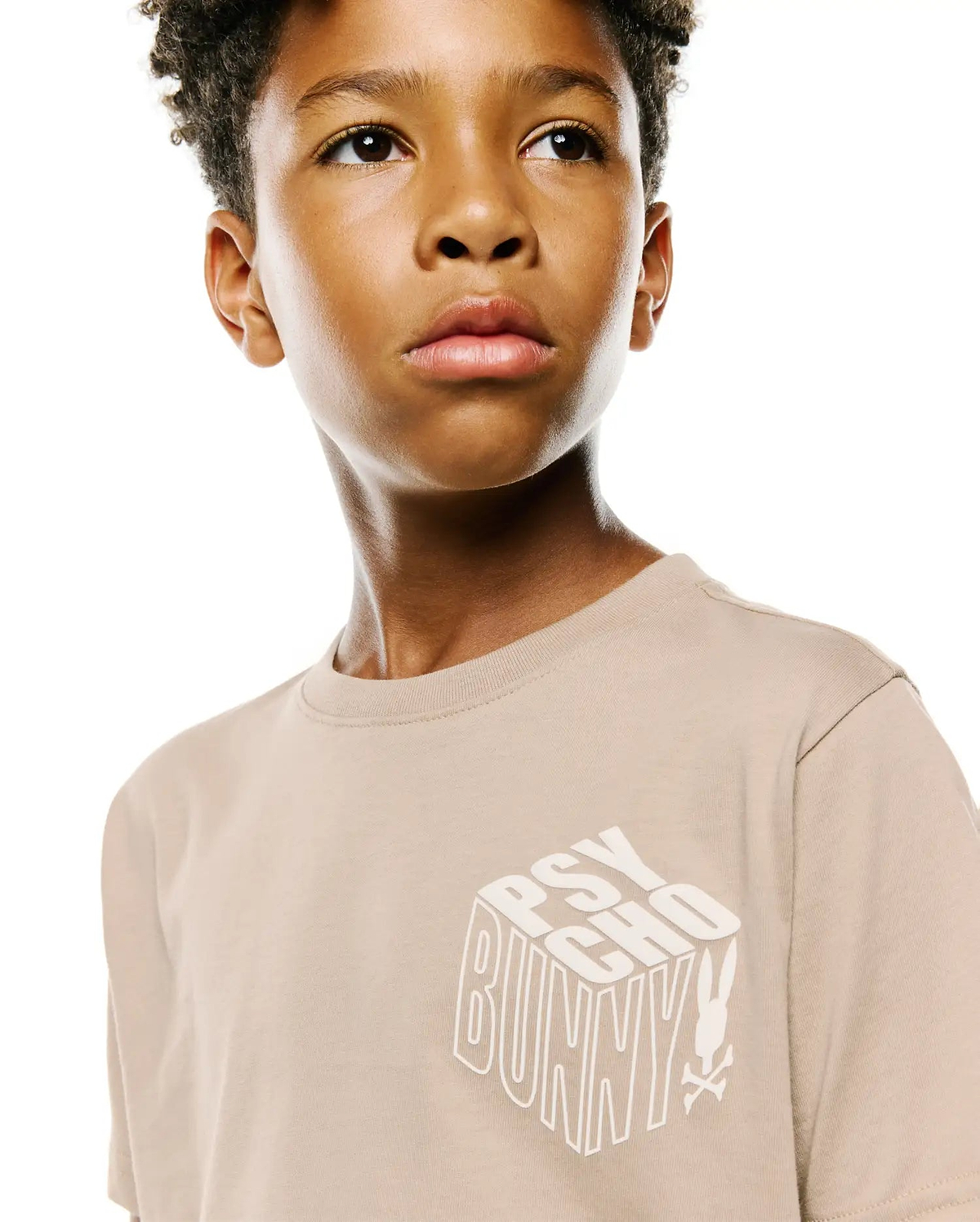 Kids Conan Back Graphic Tee in beige, featuring a classic fit and a large white 3D-effect PSYCHO BUNNY text graphic with the iconic bunny skull logo on the smooth jersey knit front.