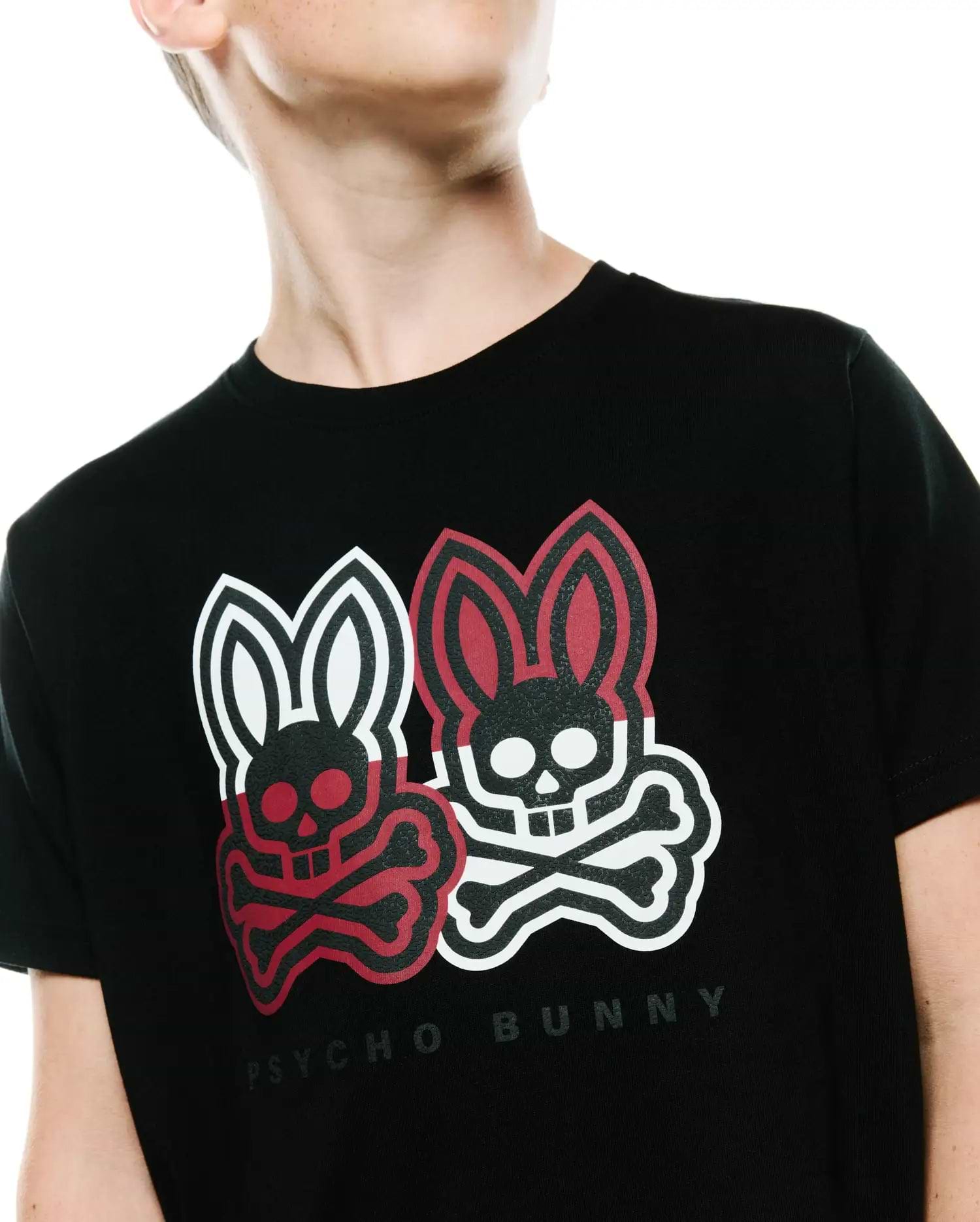 Kids Ledger Graphic Tee, a black classic fit jersey t-shirt featuring a large chest graphic of two Psycho Bunny skull logos, one red and one white, with crossbones and Psycho Bunny text.