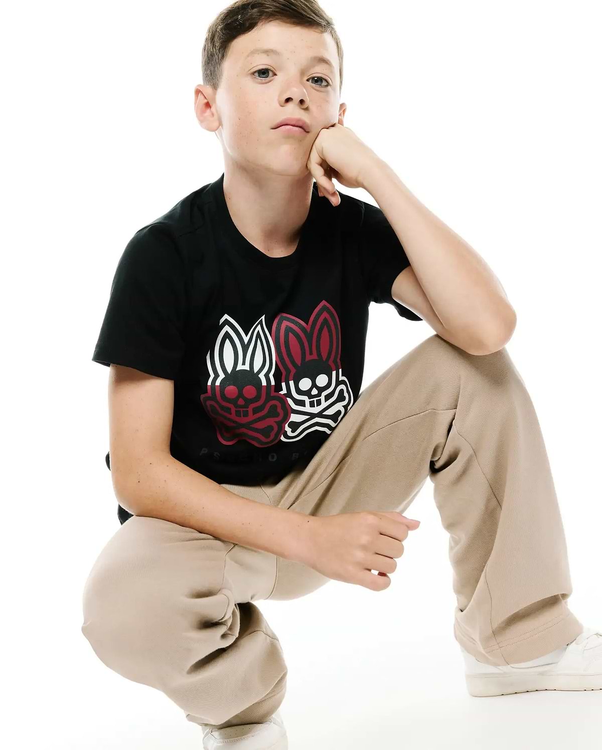 Kids Ledger Graphic Tee. Black classic fit jersey tee with a large central chest graphic featuring two Psycho Bunny skull logos, one red and one white, and Psycho Bunny text below.