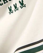 Kids Mike Graphic Jersey Tee in white jersey knit, featuring multiple small embroidered dark green Psycho Bunny skull logos and a bottom stripe design with dark green and black accents.