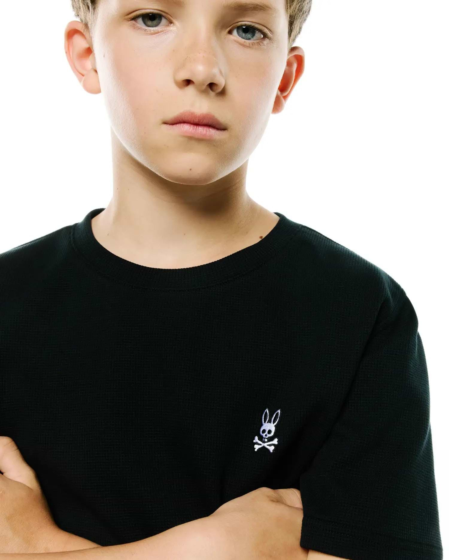 Black Kids Maxton Waffle Tee, a classic fit crewneck t-shirt with a textured waffle knit and a small embroidered white Psycho Bunny skull logo on the left chest.