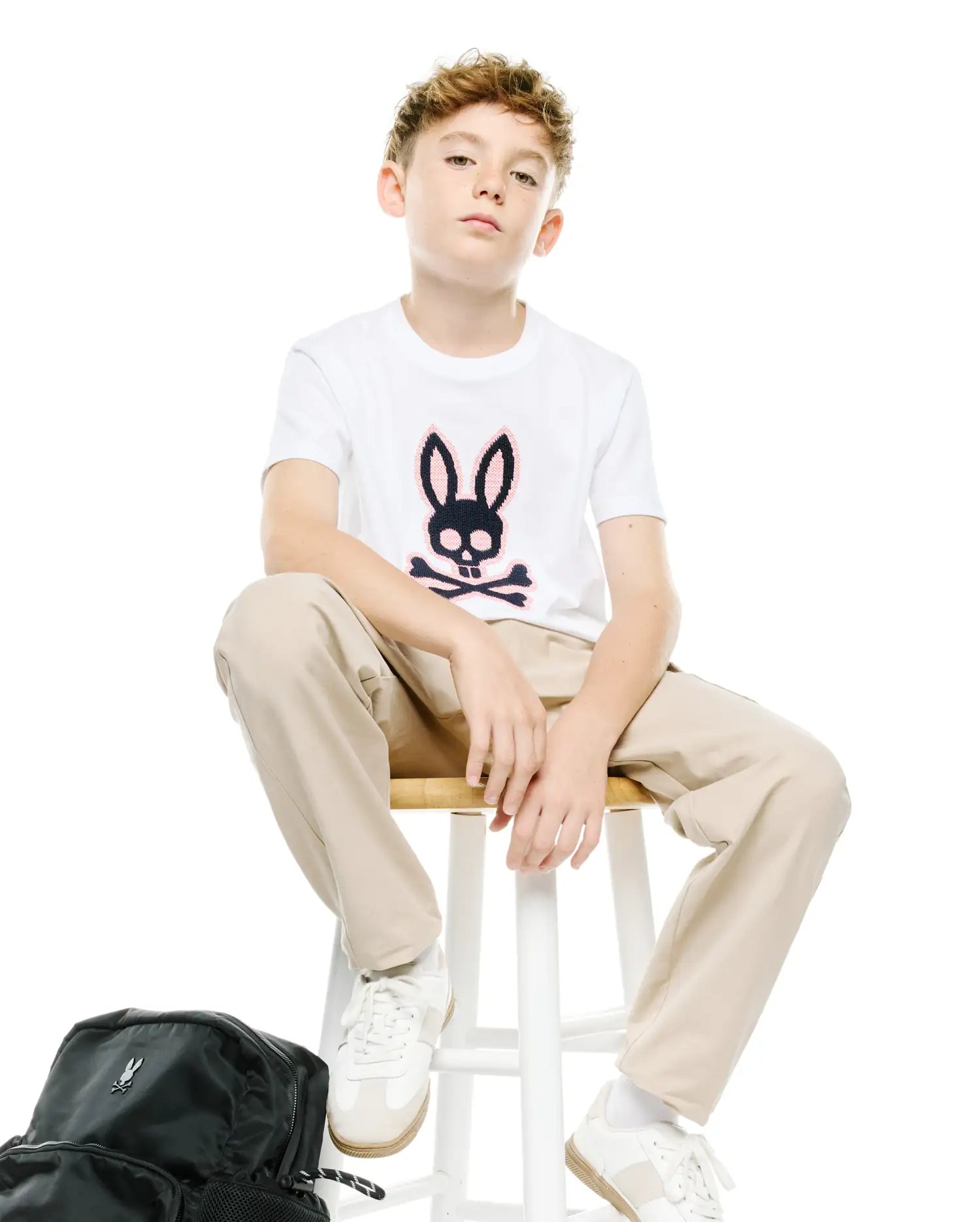 Kids' Samson Pima Graphic Tee: White classic fit pima cotton jersey t-shirt featuring a large black, pink, and blue Psycho Bunny skull logo on the chest, paired with relaxed khaki pants. (4)