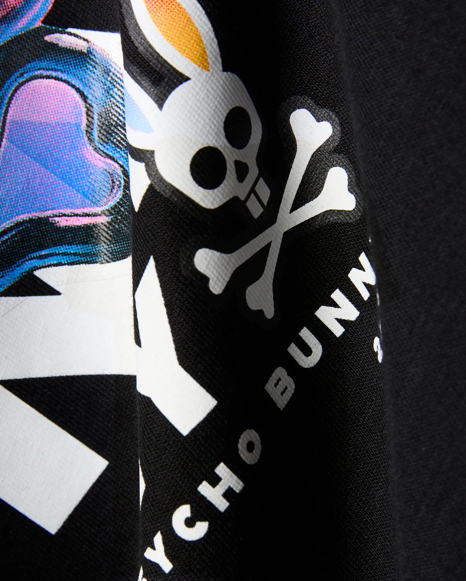 Kids Kenji Graphic Tee in black jersey knit, featuring a large vibrant graphic print with pink, blue, purple accents, and the white Psycho Bunny skull and crossbones logo with yellow ears and text.