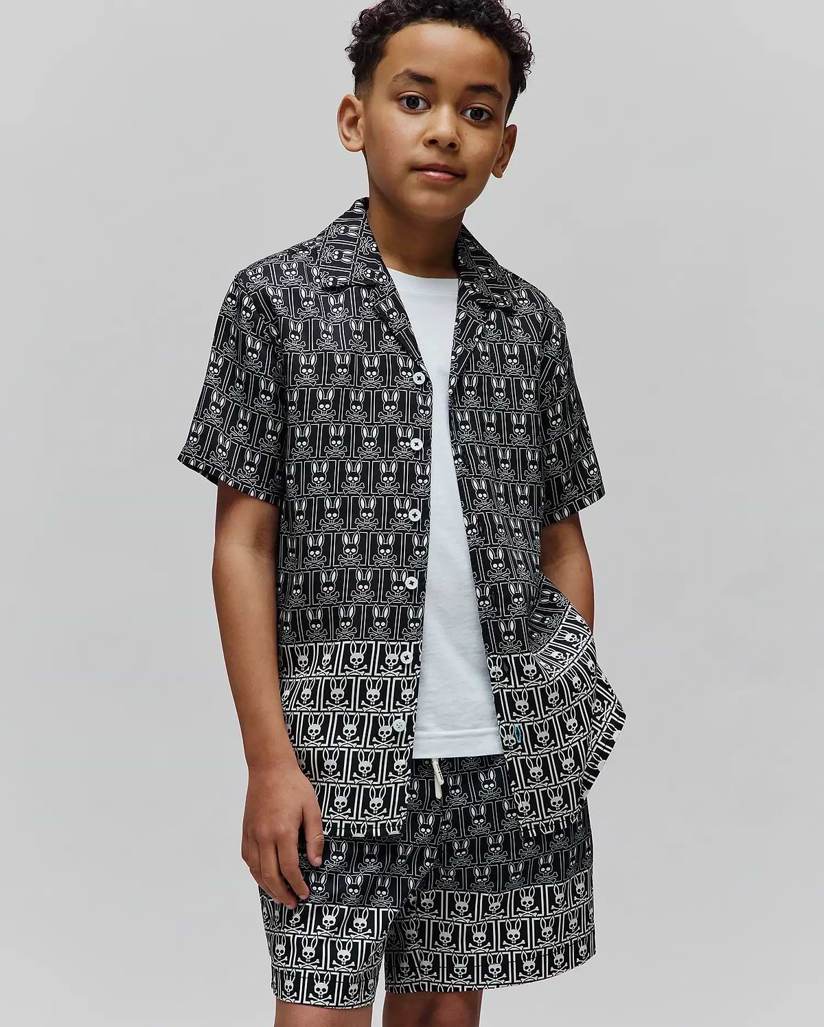 Kids Keon Tencel Shirt and matching shorts in a relaxed fit, featuring a black background with an all-over white Psycho Bunny skull logo pattern and white buttons.