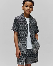 Kids Keon Tencel Shirt and matching shorts in a relaxed fit, featuring a black background with an all-over white Psycho Bunny skull logo pattern and white buttons.