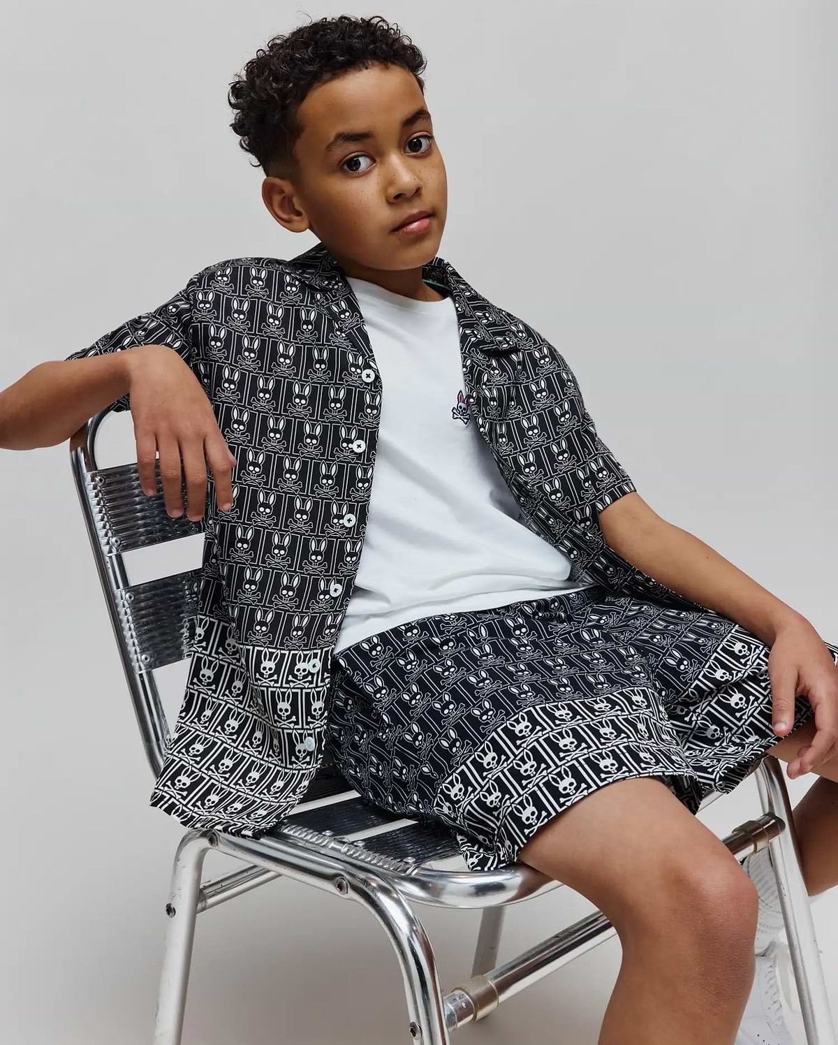 Kids Keon Tencel Shirt, a relaxed fit black and white allover Psycho Bunny skull pattern button-up, over a white jersey tee with a small embroidered logo, and matching Tencel shorts.