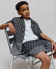 Kids Keon Tencel Shirt, a relaxed fit black and white allover Psycho Bunny skull pattern button-up, over a white jersey tee with a small embroidered logo, and matching Tencel shorts.
