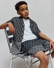 Kids Keon Tencel Shirt, a relaxed fit black and white allover Psycho Bunny skull pattern button-up, over a white jersey tee with a small embroidered logo, and matching Tencel shorts.